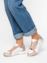 Load image into Gallery viewer, White sneakers with pink accents worn with rolled-up blue jeans on a light gray background
