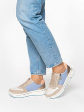 Load image into Gallery viewer, Person wearing light blue sneakers with beige accents and rolled-up jeans on a white background
