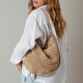 Person wearing a beige shoulder bag against a neutral background