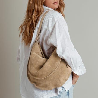Person wearing a beige shoulder bag against a neutral background
