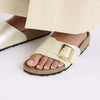 White sandal with gold buckle on a white background