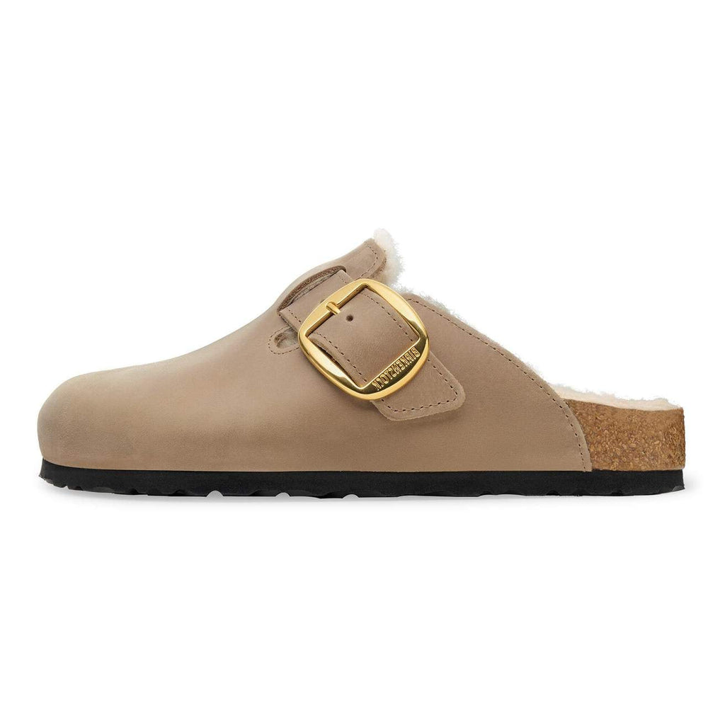 Beige clog shoe with a gold buckle on a white background
