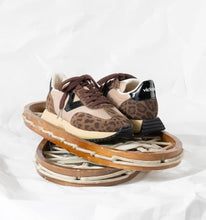 Load image into Gallery viewer, Pair of leopard print sneakers on a wooden stand with a white background
