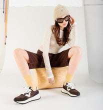 Load image into Gallery viewer, Person sitting on a bean bag chair wearing a white sweater, brown shorts, and brown sneakers.
