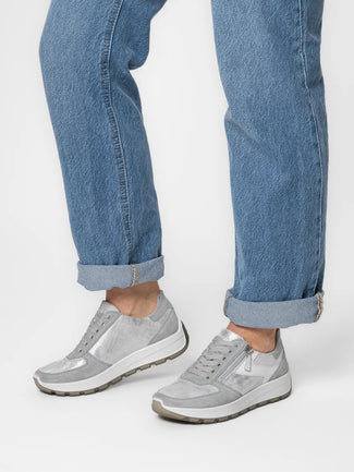 Gray sneakers worn with rolled-up blue jeans on a white background