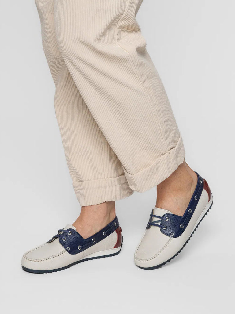 White shoes with blue accents worn with beige pants on a white background