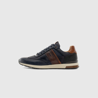 A low-top leather sneaker in navy blue with brown leather panels and a cream-colored midsole, shown in a side profile on a light gray background.