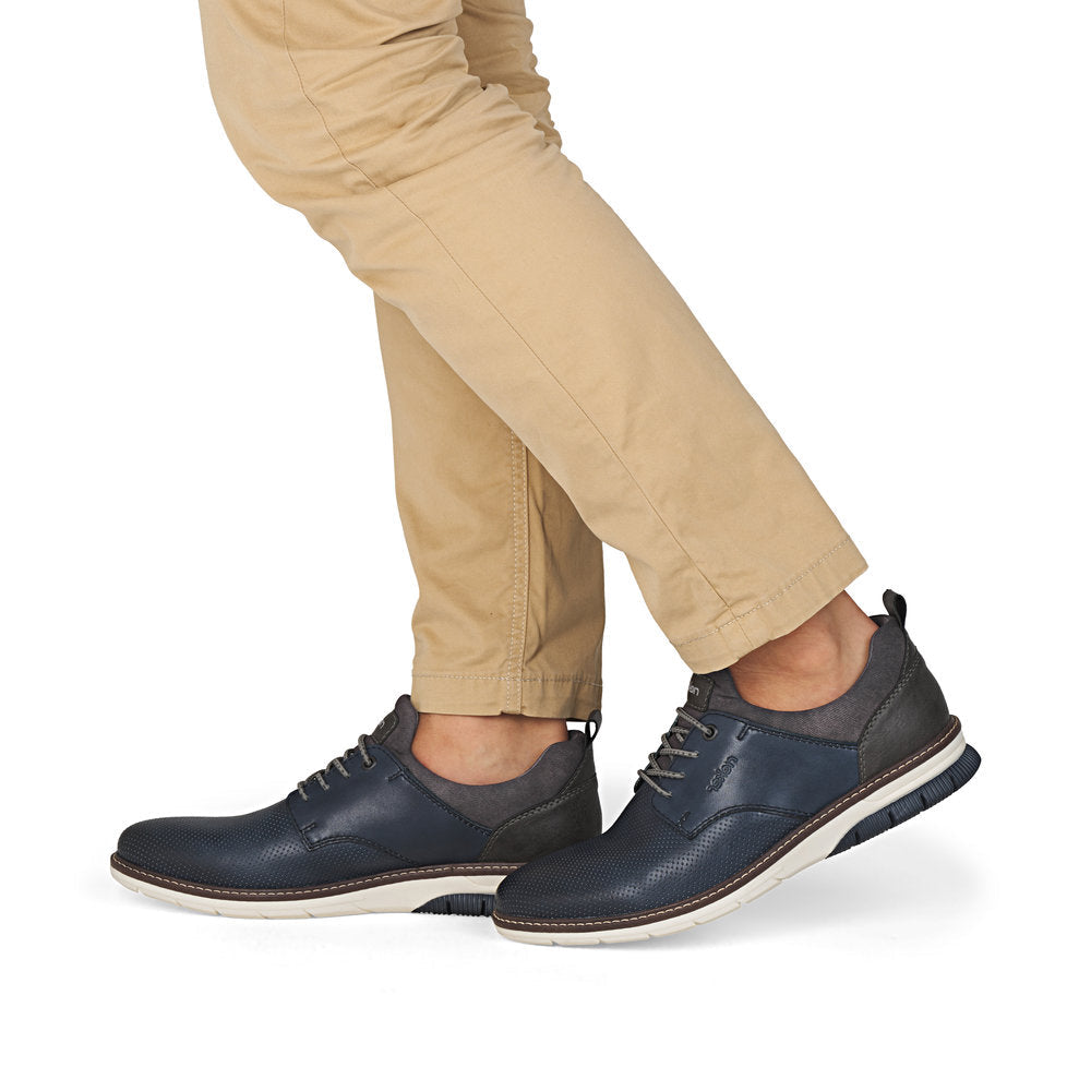 Navy leather shoes worn with beige pants on a white background