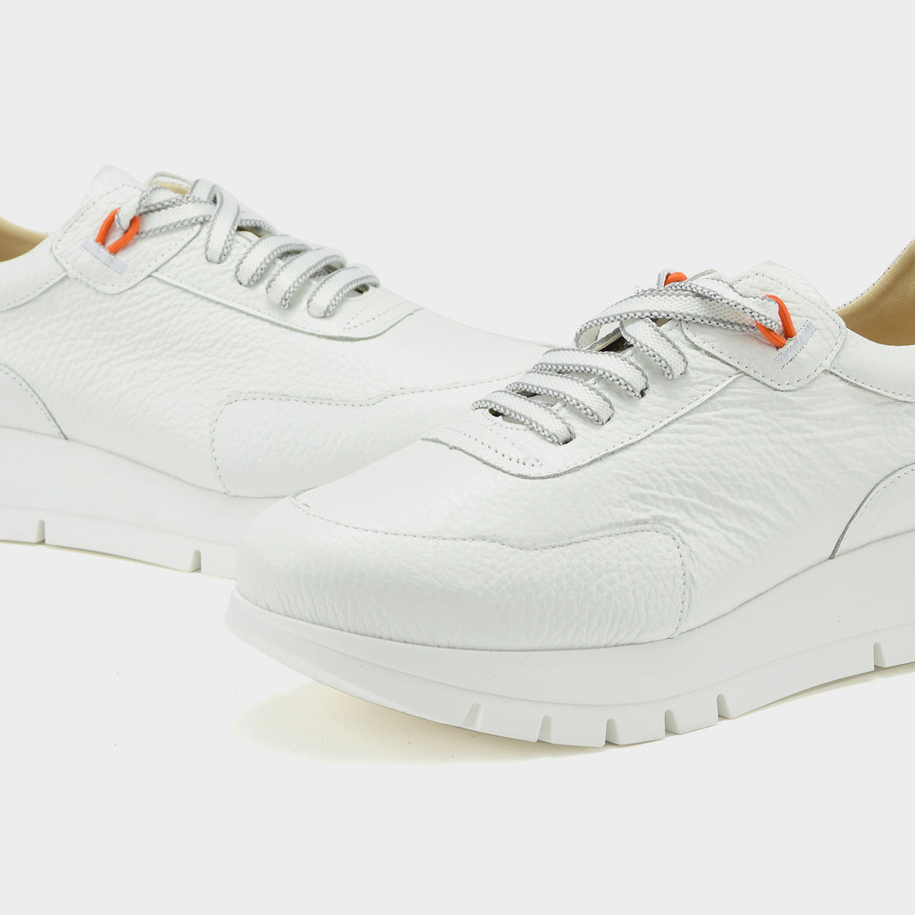 White sneakers with orange accents on a light gray background