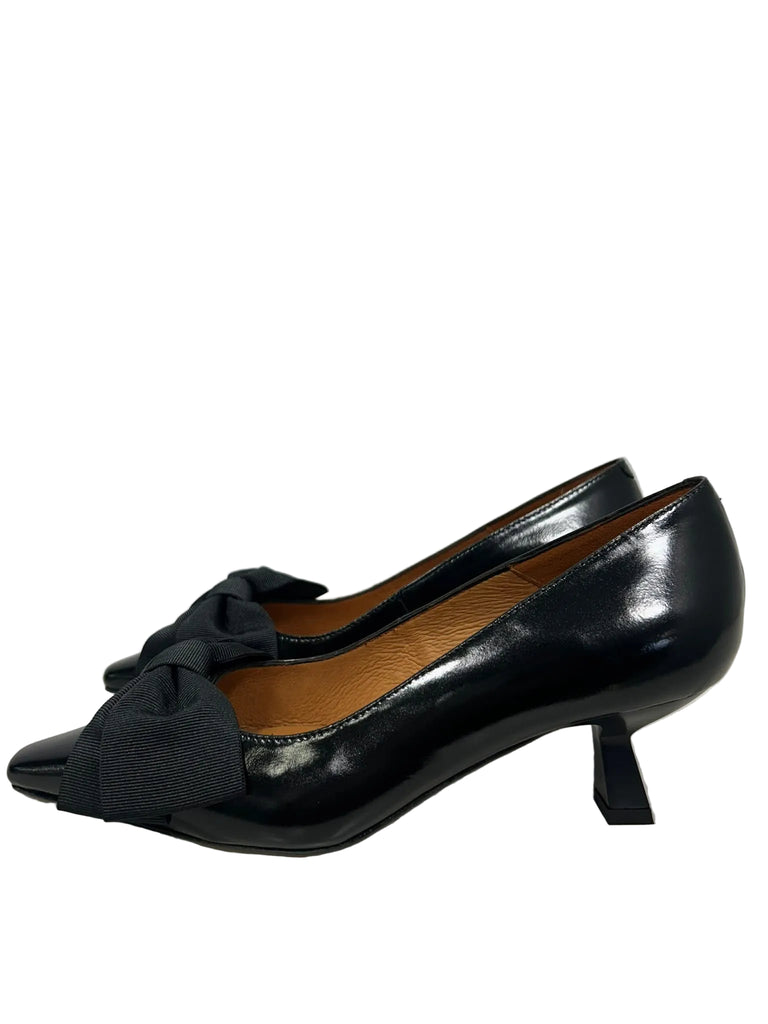 A pair of black pointed-toe pumps with a wide fabric bow detail across the vamp and a low kitten heel, shown against a plain light gray background.