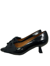 Load image into Gallery viewer, A pair of black pointed-toe pumps with a wide fabric bow detail across the vamp and a low kitten heel, shown against a plain light gray background.
