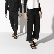 Load image into Gallery viewer, Two people wearing black pants and sandals on a white background
