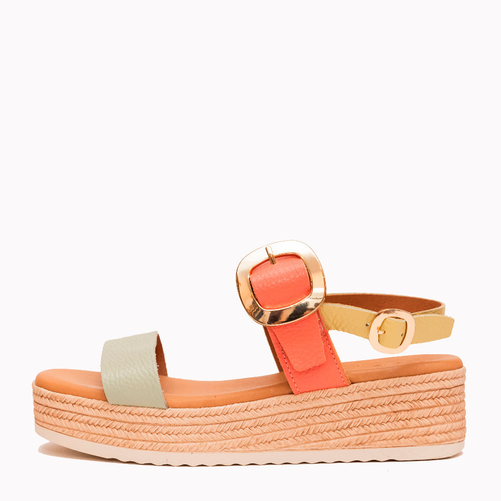Sandal with coral strap and gold buckle on a white background