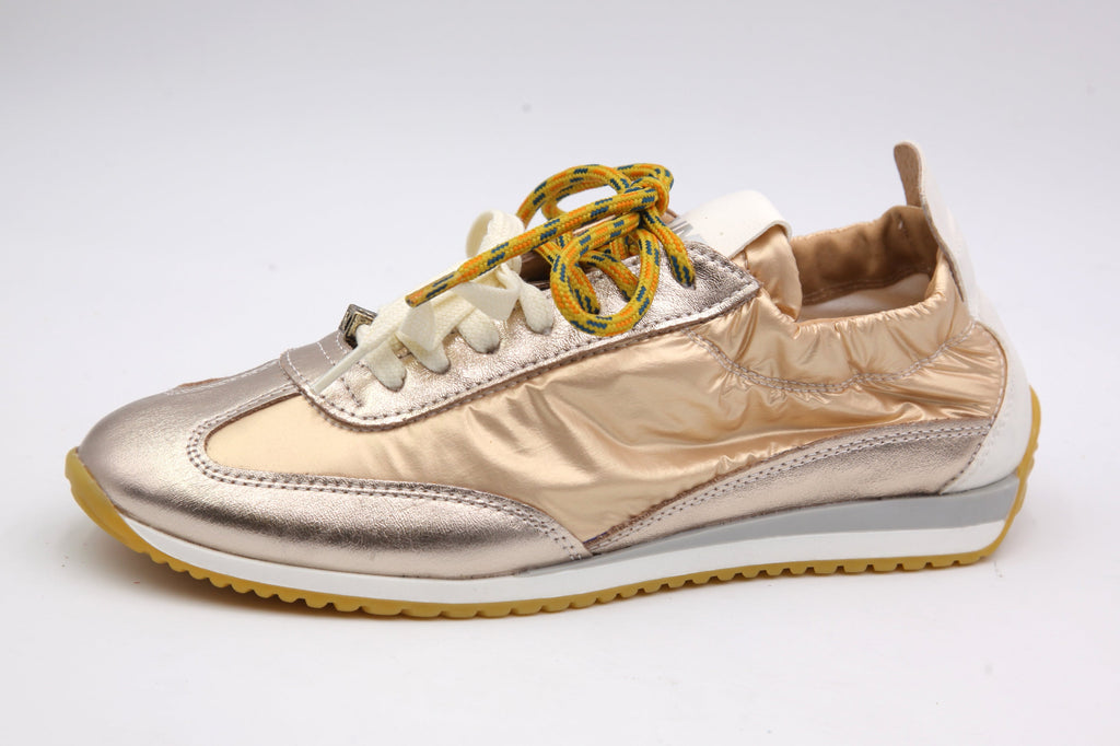 Gold sneaker with white sole on a light gray background