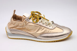 Gold sneaker with white sole on a light gray background
