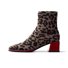 Load image into Gallery viewer, A single ankle boot with a beige and black leopard print knit upper and a glossy red block heel, shown in profile against a white background.
