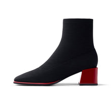 Load image into Gallery viewer, A black ribbed ankle boot with a chunky red block heel and a thin red line along the sole, shown in a side profile on a white background.
