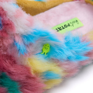 A single fuzzy slip-on mule sandal in a pastel tie-dye pattern of pink, blue, green, and yellow, shown from a side profile on a white background.