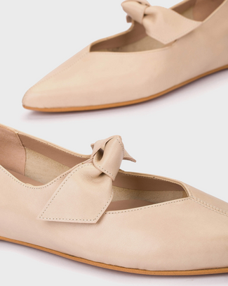 Beige flat shoe with a bow on a light gray background