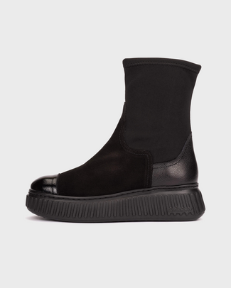 A black ankle boot with a matte black fabric upper, a glossy black cap toe, and a chunky black platform sole, shown in a side profile on a light gray background.
