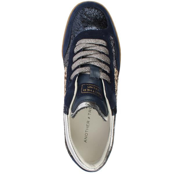A top-down view of a navy blue sneaker with textured snakeskin and leopard print panels, metallic silver laces, and a white interior lining.