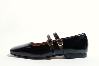 Black patent leather shoe with a strap on a white background