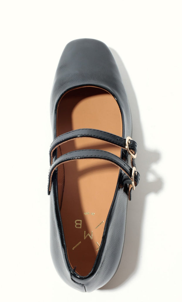 Black flat shoe with a strap on a white background