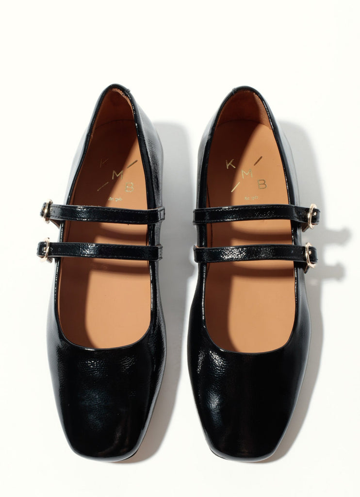 Black patent leather shoes with a strap on a white background