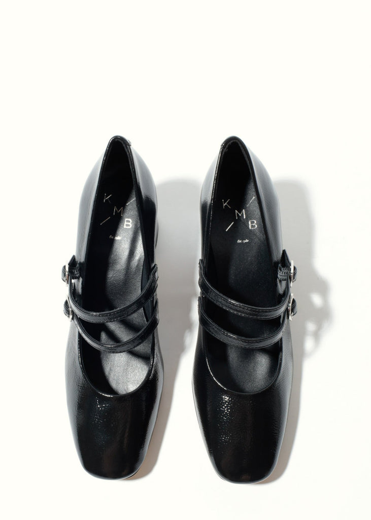 Pair of black high-heeled shoes with buckles on a white background