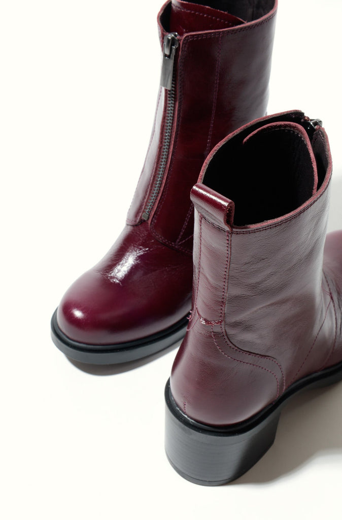 Pair of maroon ankle boots with a zipper on a white background