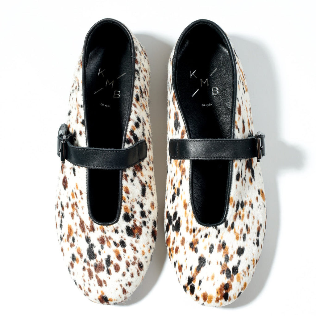 Pair of animal print shoes with black straps on a white background