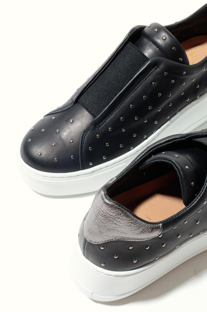 Black slip-on shoes with white soles on a light gray background