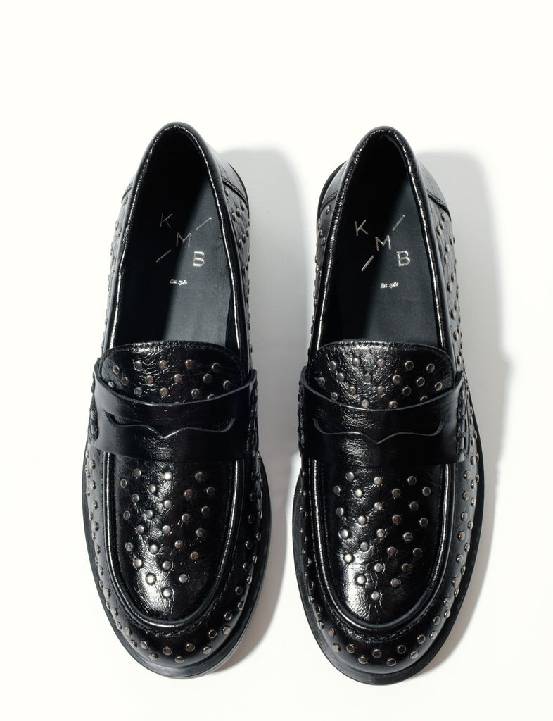 Pair of black loafers with studded details on a white background
