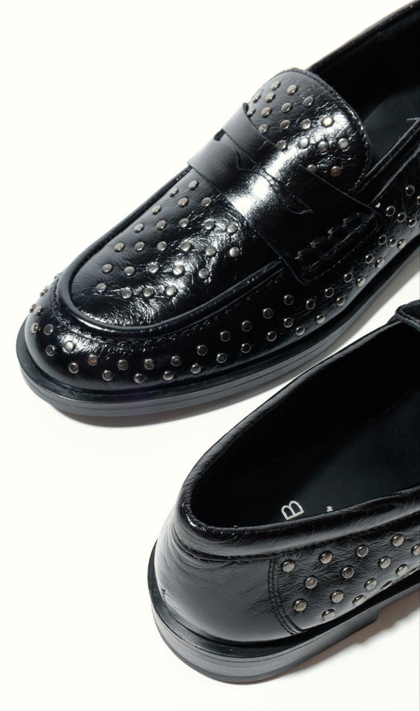 Black loafers with studded details on a white background