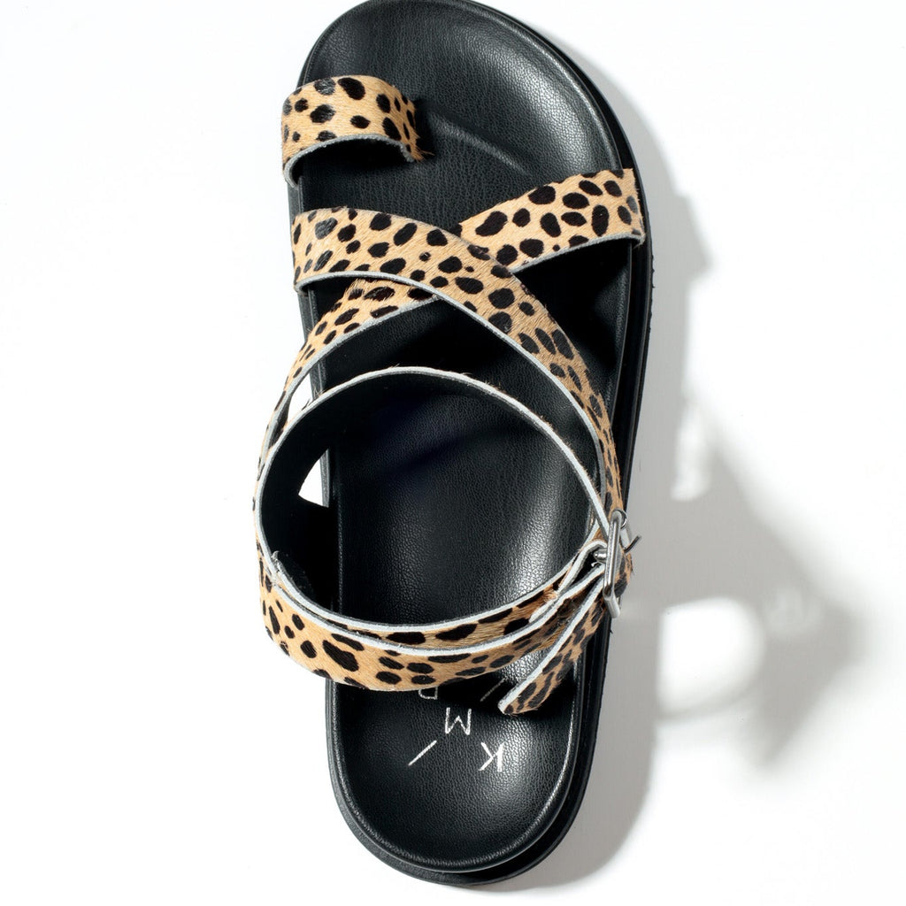 Black sandal with leopard print straps on a white background