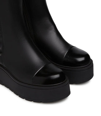 Black platform boot with ruffled detail on a white background