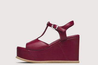 Maroon high-heeled sandals worn by a person on a light wooden floor.