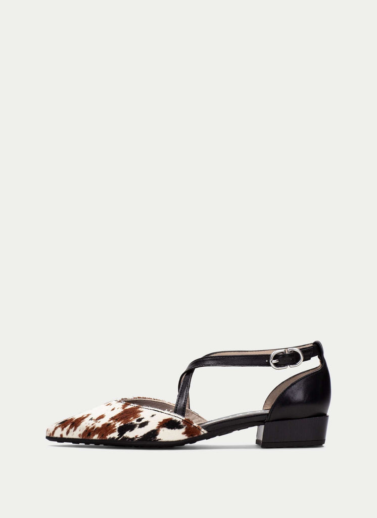 Black and brown cow print flat shoe on a white background