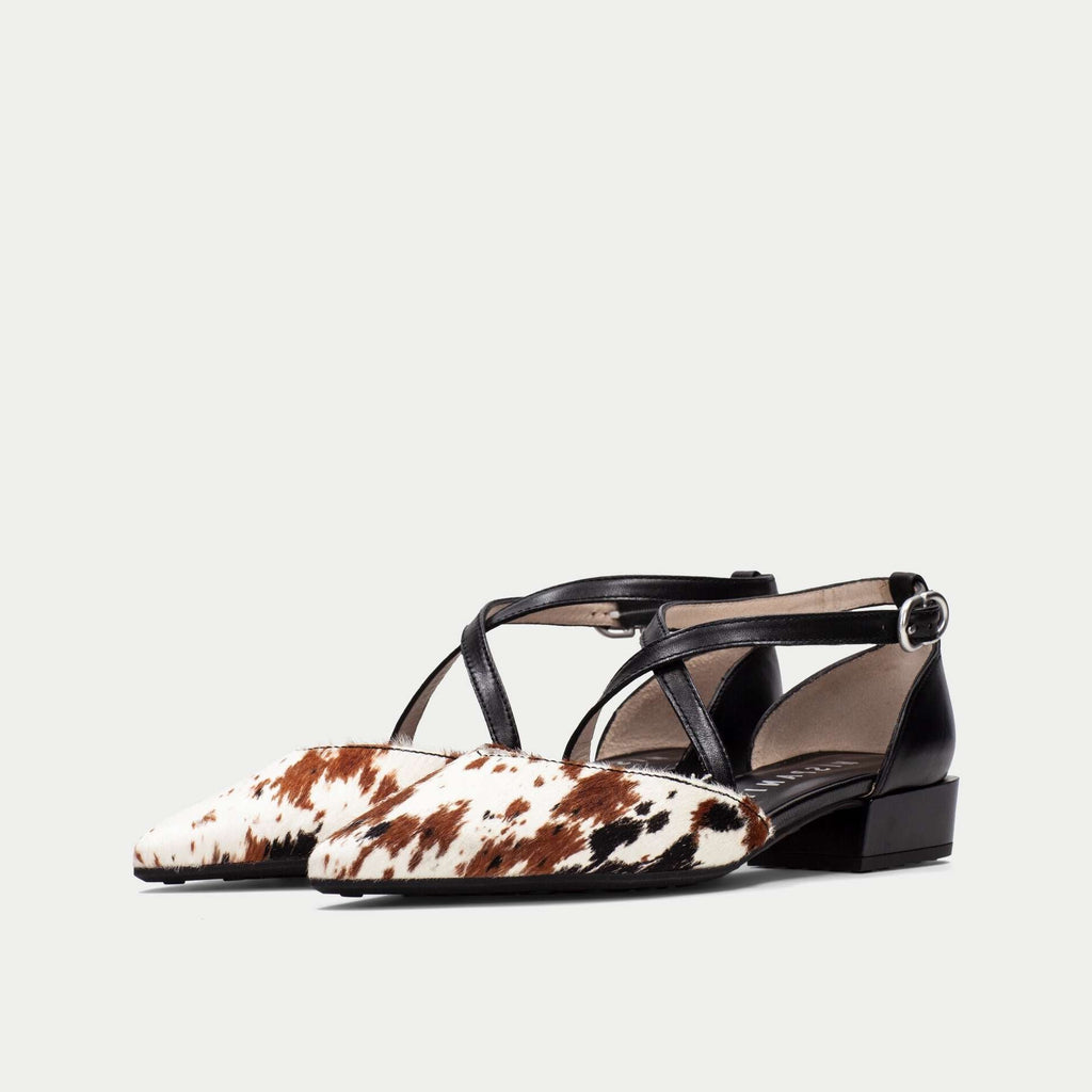 Black and white cow print shoes on a light gray background