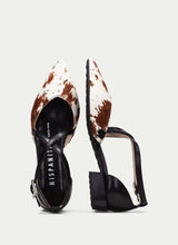 Load image into Gallery viewer, heeled shoes with cow print and black straps on a light gray background
