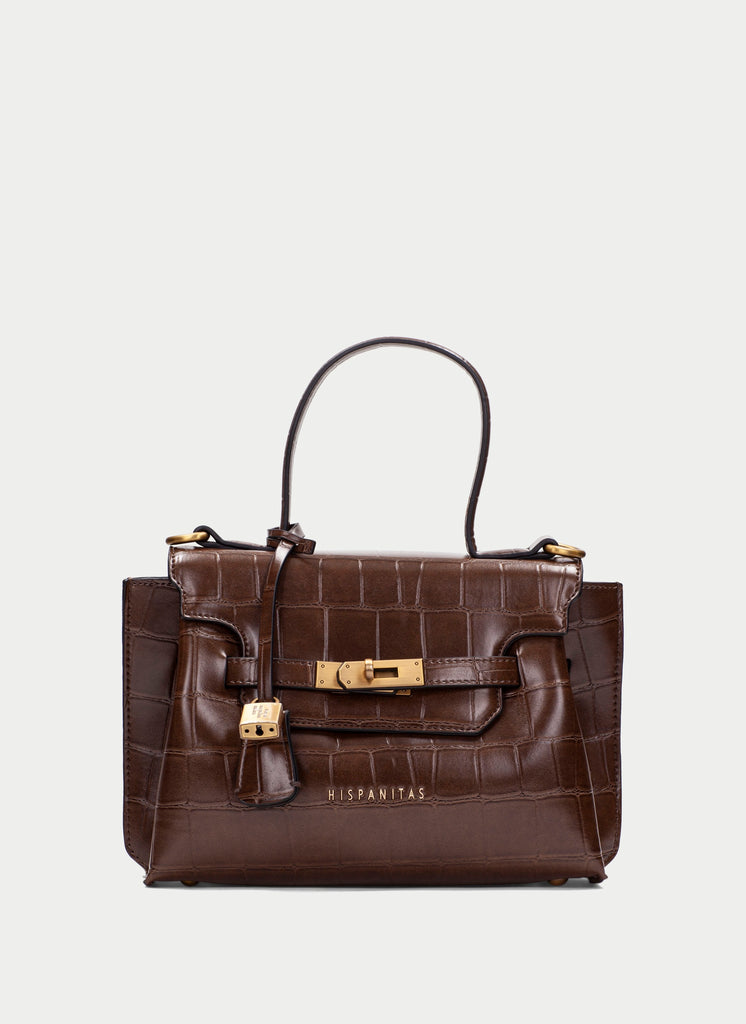 A dark brown crocodile-embossed leather handbag with gold-tone hardware and a top handle, shown against a light gray background. The brand name 'WISPANITAS' is printed in gold on the front.