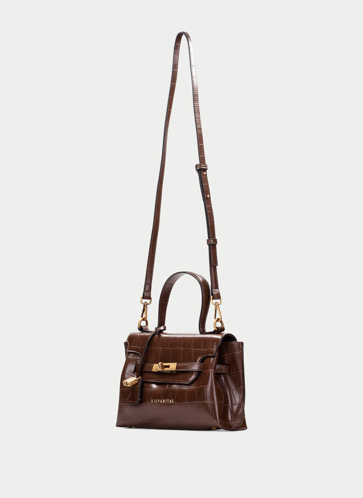 A dark brown crocodile-embossed leather handbag with a top handle, a long shoulder strap, and gold-tone hardware, shown against a light gray background.