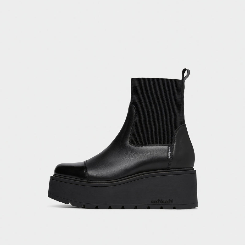 A black platform Chelsea boot with a ribbed knit ankle cuff, shown in a side profile against a light gray background.