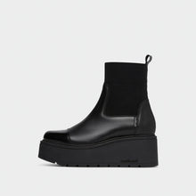 Load image into Gallery viewer, A black platform Chelsea boot with a ribbed knit ankle cuff, shown in a side profile against a light gray background.
