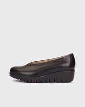 Load image into Gallery viewer, A black leather slip-on wedge shoe with a chunky lug sole, shown in a side profile view against a light gray background.
