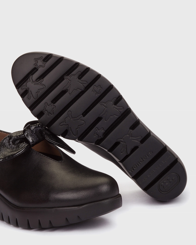 Black shoe with a textured sole on a white background