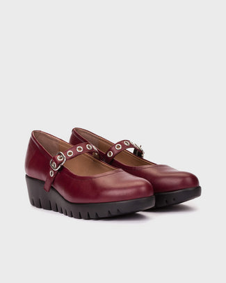 Maroon shoe with a strap and buckle on a light gray background