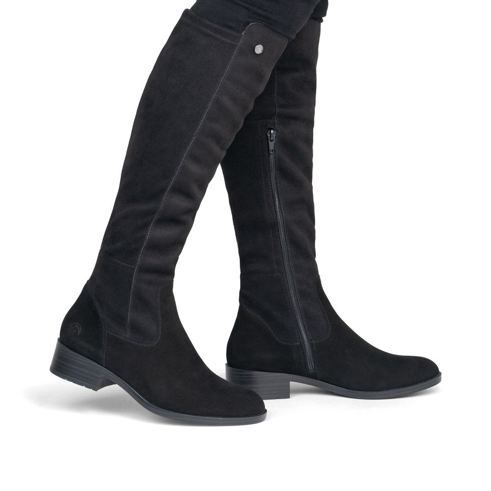 A pair of black suede over-the-knee boots with side zippers, shown on a model's legs against a plain white background.