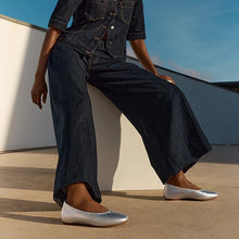 Load image into Gallery viewer, Person wearing dark denim outfit with silver flats on a rooftop.
