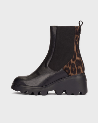 A black leather Chelsea-style ankle boot with a brown and black leopard print side panel, a black elastic side gore, and a chunky lug sole, shown against a light gray background.